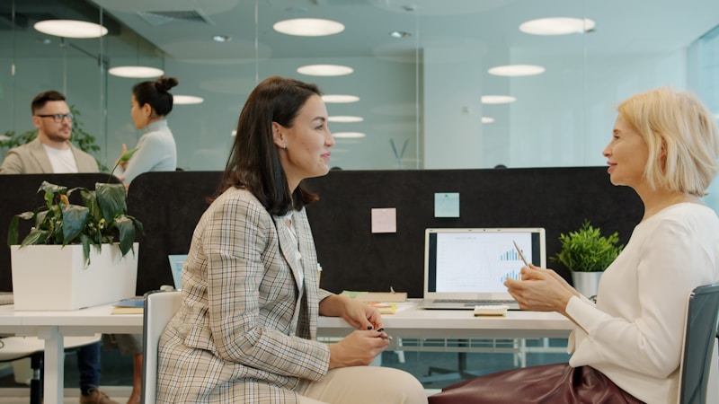 A case manager and a client sit together at a desk, looking at a laptop and a printed form.